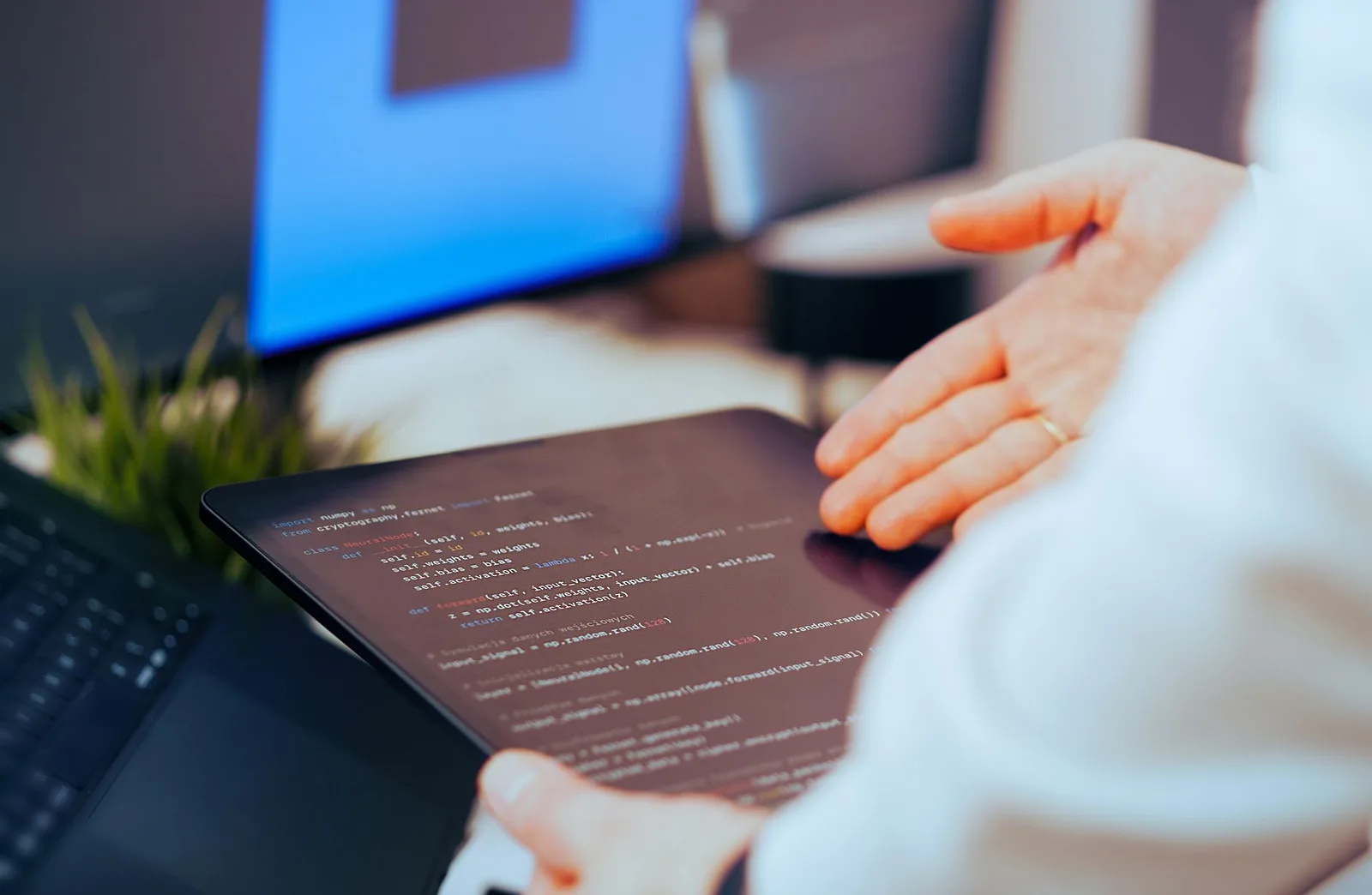 Person coding on a tablet beside a laptop