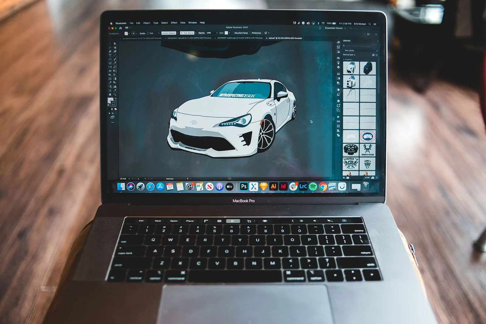 Laptop displaying a digital illustration on a dark desk