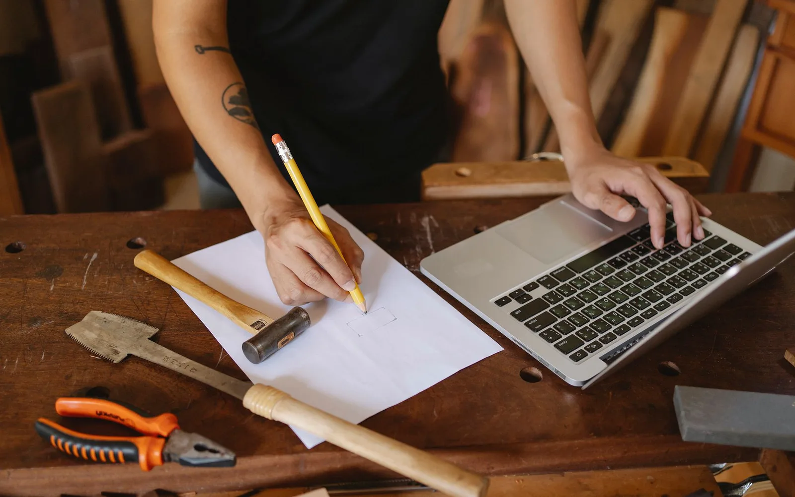 Engineer sketching beside a laptop and tools